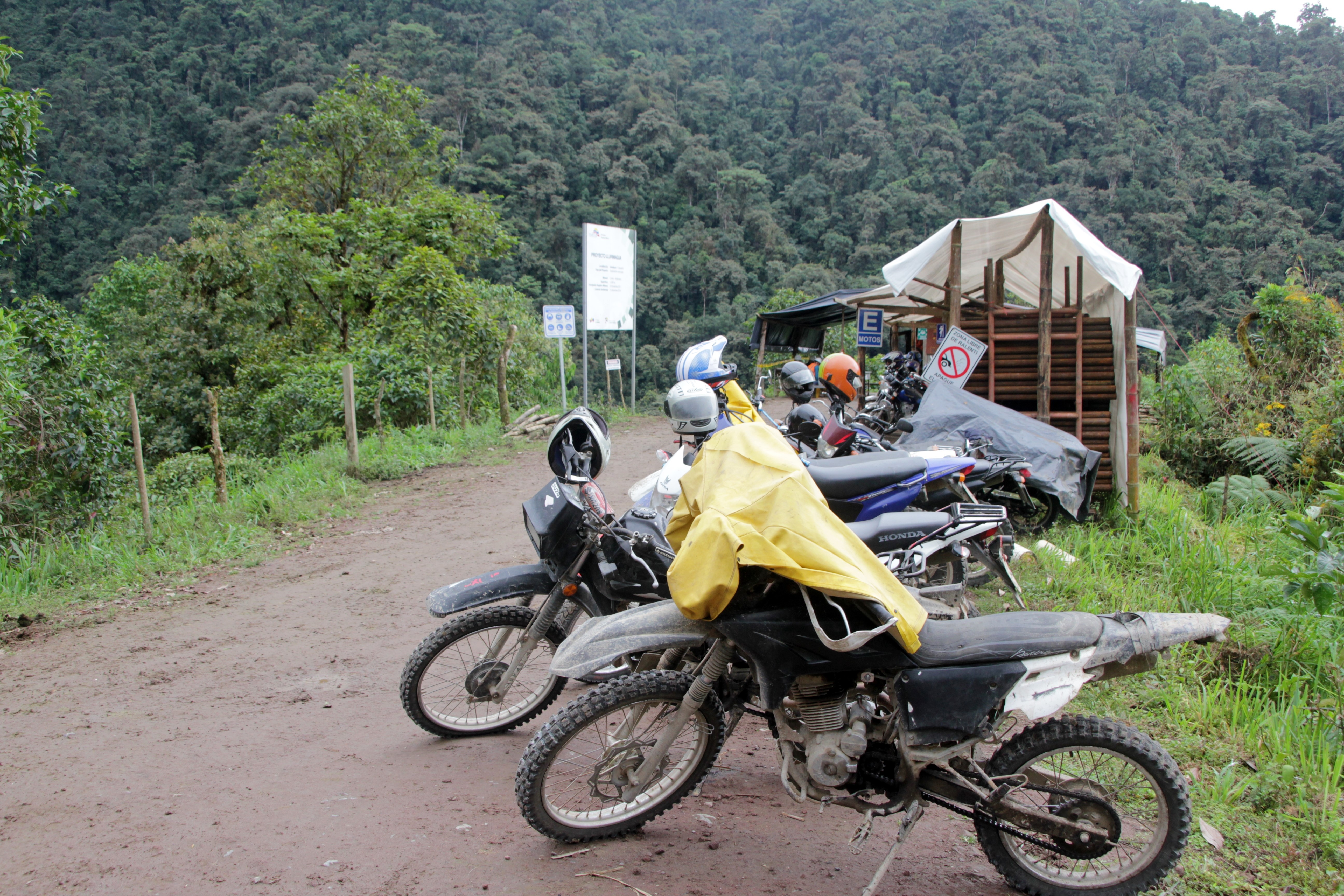 A l'entrée du campement, les motos des ouvriers devant la montagne verdoyante (© Jérôme Decoster).