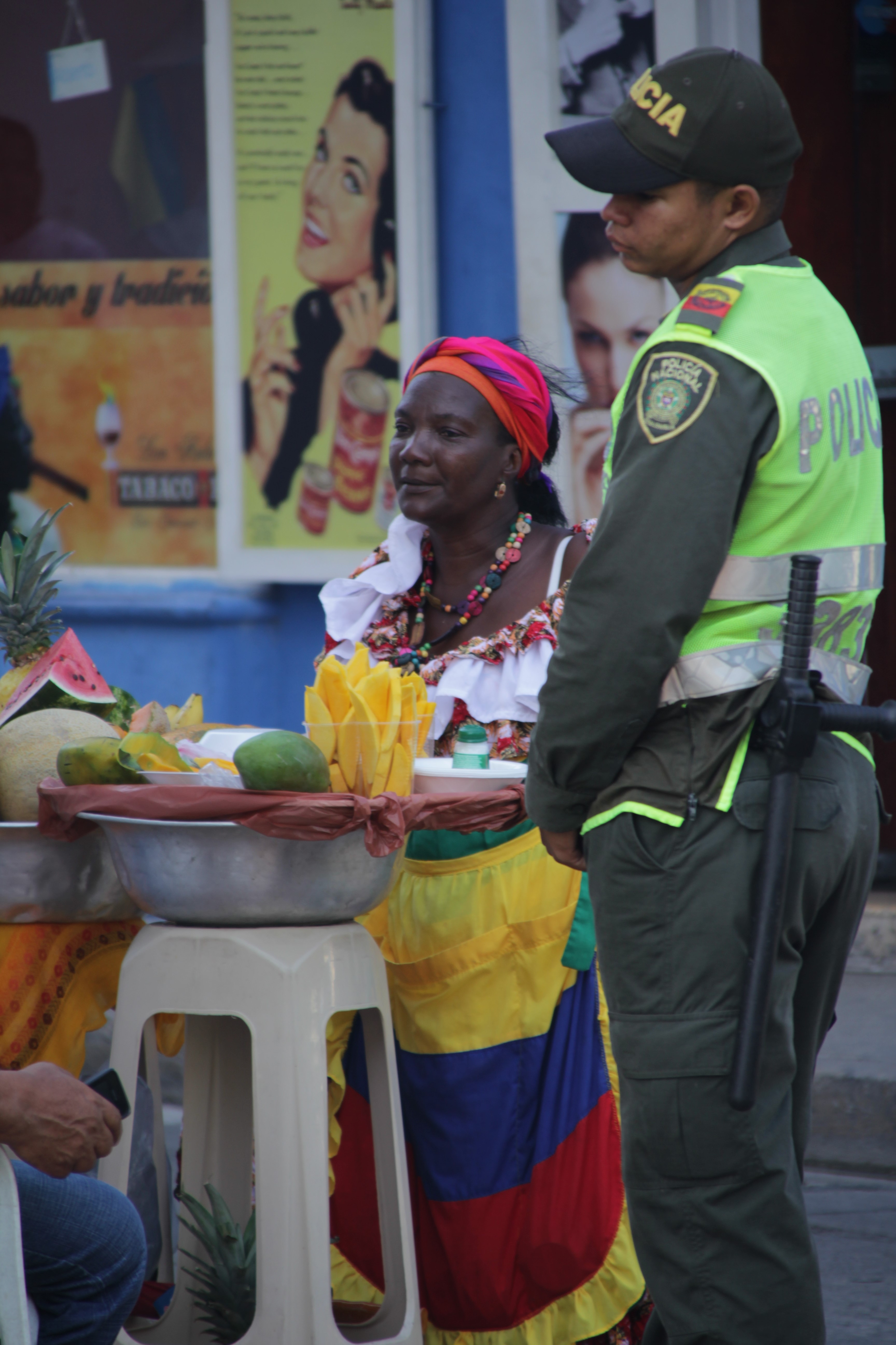 Une femme vend des fruits découpés aux côtés d’un des nombreux policiers présents dans le centre (© Jérôme Decoster).